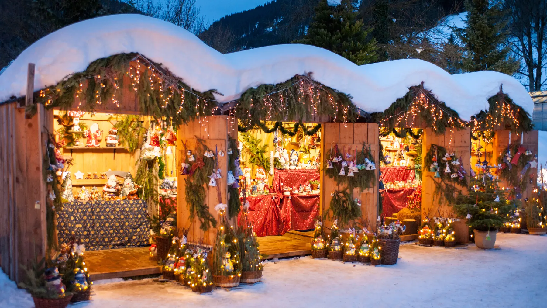 Schneebedeckte Marktstände in der Dämmerung, die Auslagen warm beleuchtet